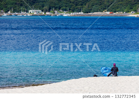 Tourists packing up their tents on a white sand beach. Beautiful coral reefs and schools of tropical fish. Kabi Island, Zamami, Kerama Islands, Shimajiri District, Okinawa Prefecture Tourists packing up their tents on a white sand beach. Beautiful coral reefs and schools of tropical fish. Kabi Island, Zamami, Kerama Islands, Shimajiri District, Okinawa Prefecture 132772345