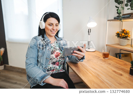 Smiling cute woman listening to music on phone 132774680