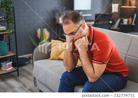 Man sitting alone at home looking sad and distraught Man sitting alone at home looking sad and distraught 132774731