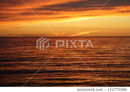 Dramatic sunset over the ocean, golden hour light reflecting on the water surface, creating a serene and peaceful scene, beautiful sky with clouds at dusk, nature background Dramatic sunset over the ocean, golden hour light reflecting on the water surface, creating a serene and peaceful scene, beautiful sky with clouds at dusk, nature background 132775996
