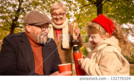 Father laughing as daughter pours tea under grandmother smile Father laughing as daughter pours tea under grandmother smile 132776104