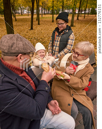 Family generations sharing food and laughter during autumn picnic Family generations sharing food and laughter during autumn picnic 132776151