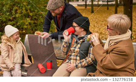 Family enjoying autumn picnic with sandwiches and coffee outdoors 132776158