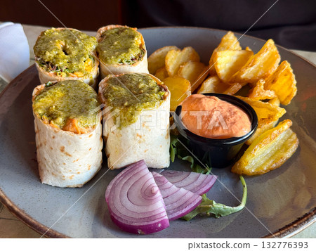Wraps with sauce, onion, and chips served in a restaurant. Texture, flavor and everyday pleasure of casual dining experience. 132776393