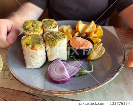 Wraps with sauce, onion, and chips served in a restaurant. Texture, flavor and everyday pleasure of casual dining experience. Wraps with sauce, onion, and chips served in a restaurant. Texture, flavor and everyday pleasure of casual dining experience. 132776394