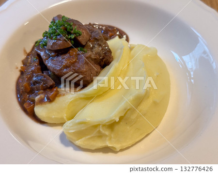 Close-up of beef with mashed potatoes and sauce in a white plate. Flavor, warmth and culinary detail capturing comfort and taste. 132776426