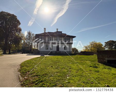 Historic building surrounded by trees and sunlight in city park. Architecture, heritage and the tranquil atmosphere of autumn day. 132776438