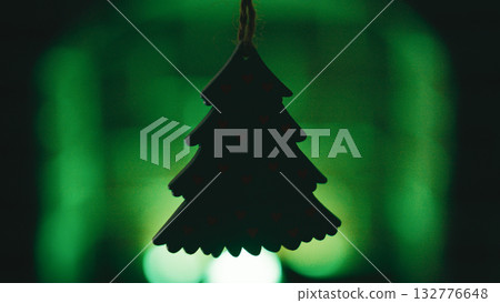 Silhouette of a small Christmas tree shape in front of a green fireplace 132776648
