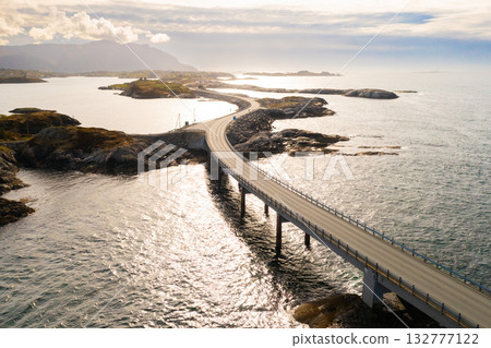 Winding Atlantic ocean road connects small rocky islands across sea water. Picturesque route through Norwegian archipelago under cloudy sky Winding Atlantic ocean road connects small rocky islands across sea water. Picturesque route through Norwegian archipelago under cloudy sky 132777122