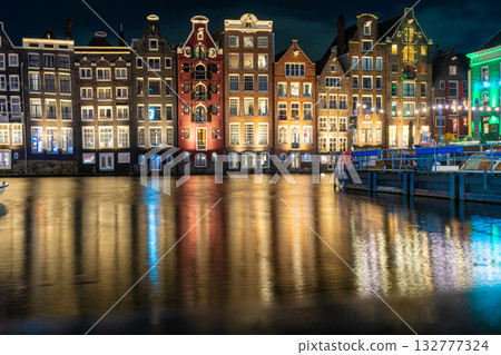 Amsterdam Netherlands night. Colorful houses canal water reflection. Sightseeing Evening street architecture with lights in windows lanterns Amsterdam Netherlands night. Colorful houses canal water reflection. Sightseeing Evening street architecture with lights in windows lanterns 132777324