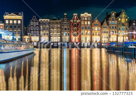 Amsterdam night. Colorful houses canal water reflection. Evening street architecture with lights in windows lanterns Amsterdam night. Colorful houses canal water reflection. Evening street architecture with lights in windows lanterns 132777325
