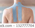 Close-up view of kinesiology tape applied to the neck and shoulder area of a woman. Physical therapy and muscle support through modern rehabilitation techniques 132777704