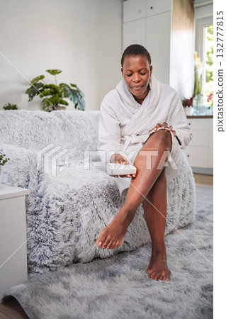 Young woman removing leg hair with an electric epilator at home 132777815
