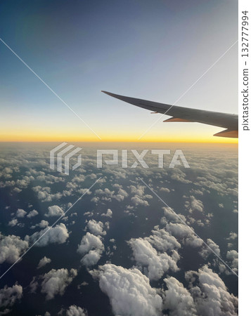 夕陽西下，飛機機翼掠過雲層。 132777994