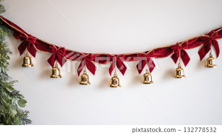 Festive red velvet garland with gold bells and greenery for holiday decoration 132778532