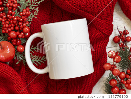 White blank coffee mug on red knitted sweater near Christmas decor, winter Holiday mockup 132779190