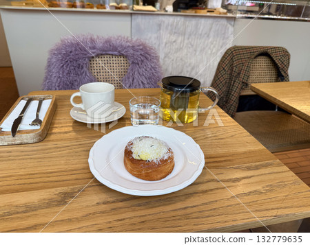 Cafe table with tea and pastry during a cozy morning break. Warmth, comfort and everyday joy in relaxed lifestyle moments. Cafe table with tea and pastry during a cozy morning break. Warmth, comfort and everyday joy in relaxed lifestyle moments. 132779635
