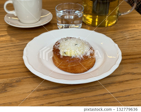 Sweet pastry on a white plate in a cafe setting. Comfort, taste and relaxation in cozy morning dining moments. Sweet pastry on a white plate in a cafe setting. Comfort, taste and relaxation in cozy morning dining moments. 132779636