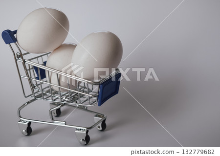 White chicken egg in a tiny shopping cart on a clean white background 132779682