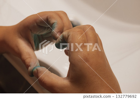 Child's paint-covered hands forming a heart gesture after a fun, creative art session 132779692
