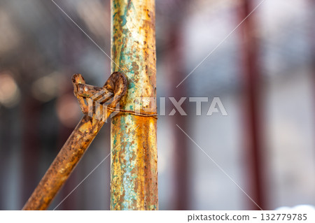 Close up shot of rusty metal pole and scaffolding on blurry construction work site background. 132779785