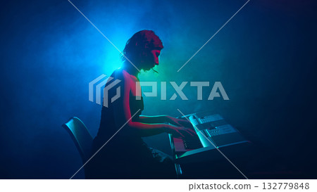 Female pianist playing electronic keyboard under blue and green light Female pianist playing electronic keyboard under blue and green light 132779848