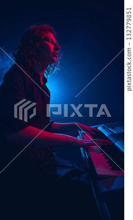 Keyboard musician performing under deep blue and red lighting 132779851