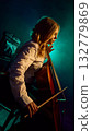 Side view of female cellist performing on stage with teal lighting 132779869