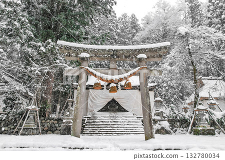 Snow falls on the World Heritage Site Shirakawa Hachiman Shrine in Shirakawa-go, with its silver-white torii gate and majestic snowscape. 132780034