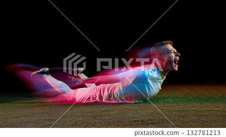 Soccer player sliding on grass celebrating victory with neon motion blur 132781213