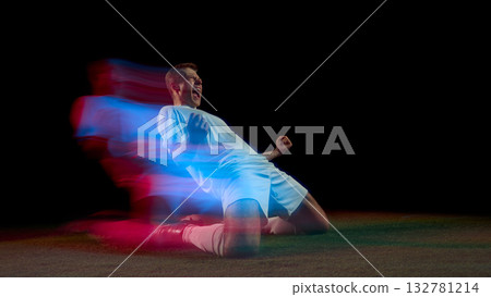 Soccer player celebrating goal on knees with red and blue motion streaks 132781214