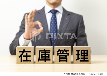一位商人擺出「OK」的手勢，旁邊立著一塊寫著「庫存管理」的積木。 132781309