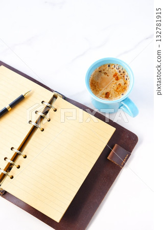 An image of someone writing in a diary while drinking a cafe latte, a coffee with plenty of milk. 132781915