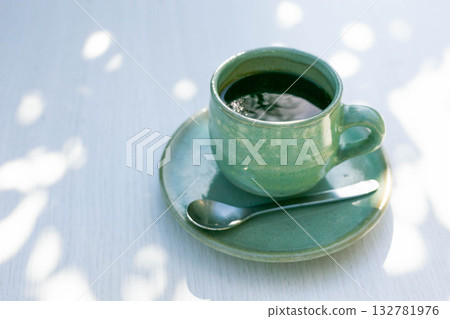 晨光透過樹葉灑在一杯綠色的咖啡上。 132781976