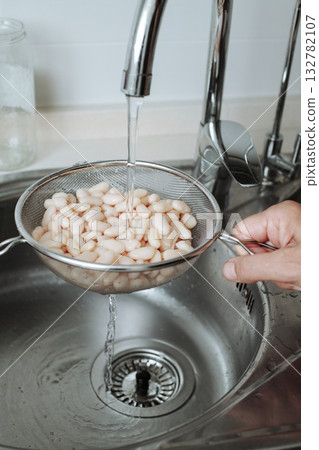 rinsing white beans in the kitchen sink rinsing white beans in the kitchen sink 132782107