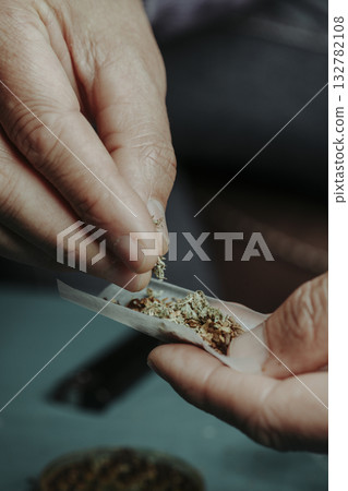 man preparing a spliff in a rolling paper 132782108