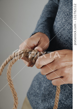 a man tying a slip knot with a jute rope 132782112