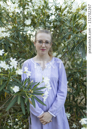 Young woman smiling in lavender dress among white flowers Young woman smiling in lavender dress among white flowers 132782267