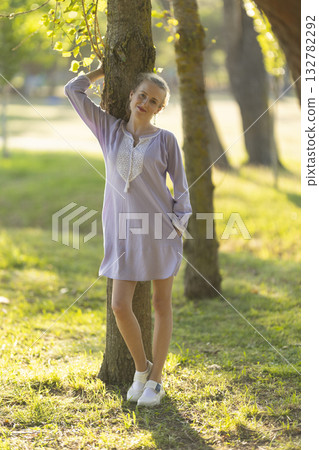 Young woman smiling while leaning against a tree Young woman smiling while leaning against a tree 132782292