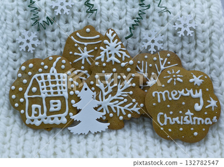 Gingerbread cookies decorated with royal icing on white knitted background, holidays greeting card Gingerbread cookies decorated with royal icing on white knitted background, holidays greeting card 132782547