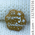 Gingerbread cookie decorated with royal icing on white knitted background, holidays greeting card 132782556