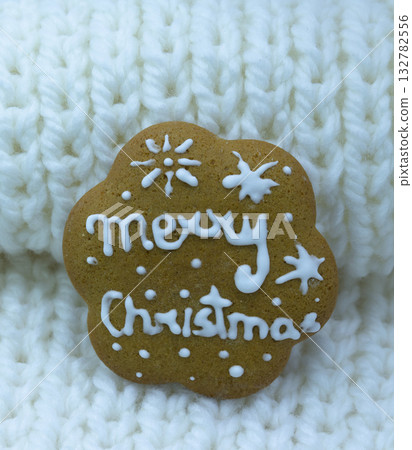 Gingerbread cookie decorated with royal icing on white knitted background, holidays greeting card 132782556