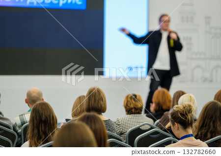 Business presentation in a conference hall with a speaker addressing an attentive audience 132782660
