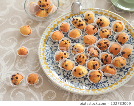 Mini chocolate cupcakes on patterned ceramic plate. Holidays and lifestyle. Food on table covered with tablecloth. Mini chocolate cupcakes on patterned ceramic plate. Holidays and lifestyle. Food on table covered with tablecloth. 132783009