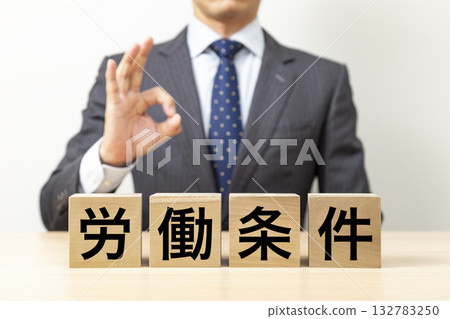 一名商人擺出「OK」的姿勢，旁邊立著一塊寫著「工作條件」的牌子。 132783250
