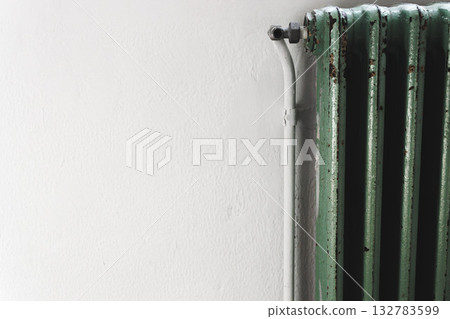 Old green radiator against white wall concept of home heating and energy efficiency. 132783599