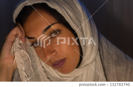Close-up of a thoughtful Muslim woman wearing a traditional headscarf and looking at the camera. Close-up of a thoughtful Muslim woman wearing a traditional headscarf and looking at the camera. 132783740