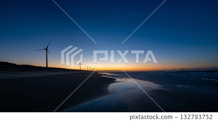 Panoramic view of wind turbines and sandy beach along the seashore at sunrise Panoramic view of wind turbines and sandy beach along the seashore at sunrise 132783752
