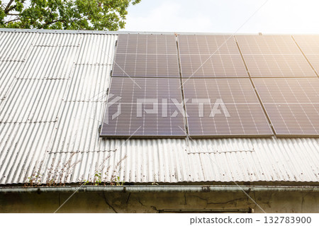 Modern solar panels mounted on an old corrugated metal roof, representing renewable energy Modern solar panels mounted on an old corrugated metal roof, representing renewable energy 132783900