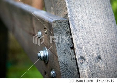 Detailed view of a wooden beam joint connected with bolts and metal fasteners, showing carpentry Detailed view of a wooden beam joint connected with bolts and metal fasteners, showing carpentry 132783919